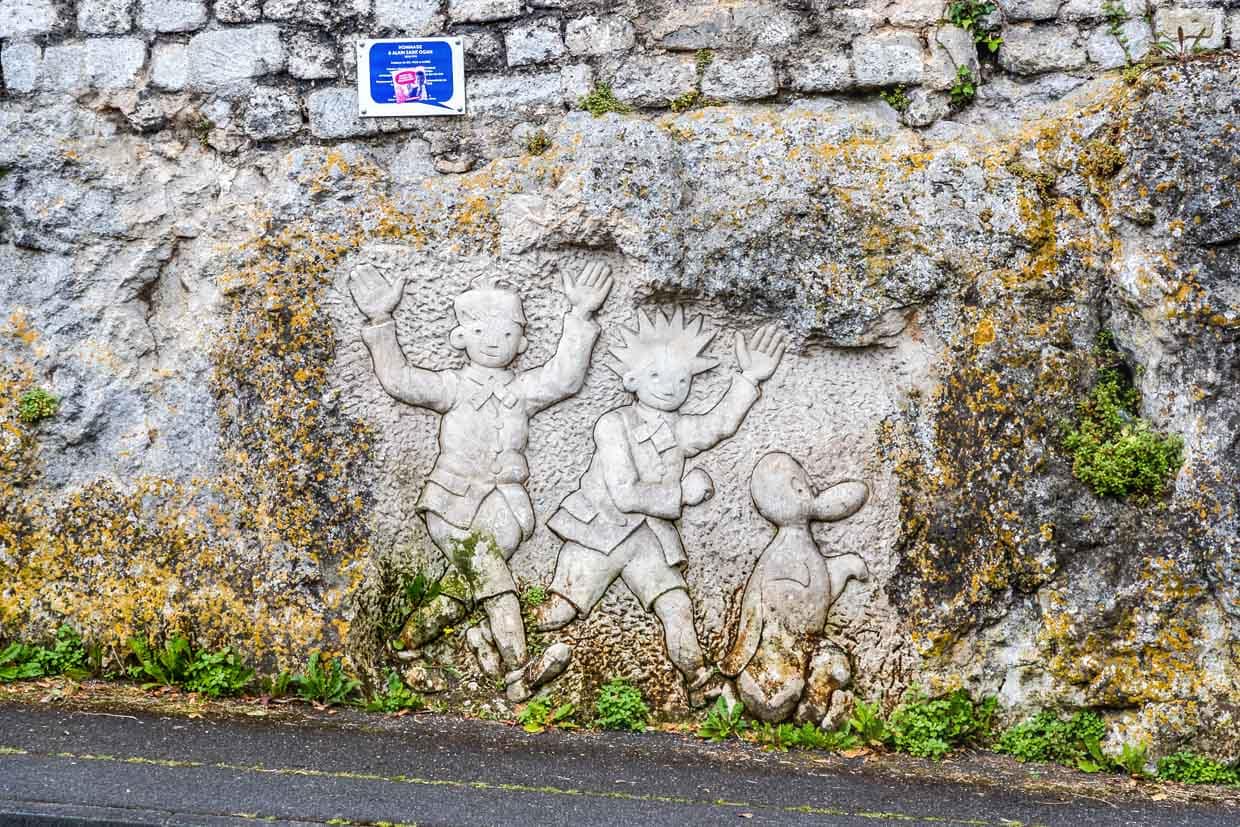 Unscheinbar als Relief neben der Autostraße, die nach Angoulême führt: Die beiden Jungen, Zig und Puce, die mit ihrem Pinguin Alfred fantastische Reisen unternehmen / © Foto: Georg Berg