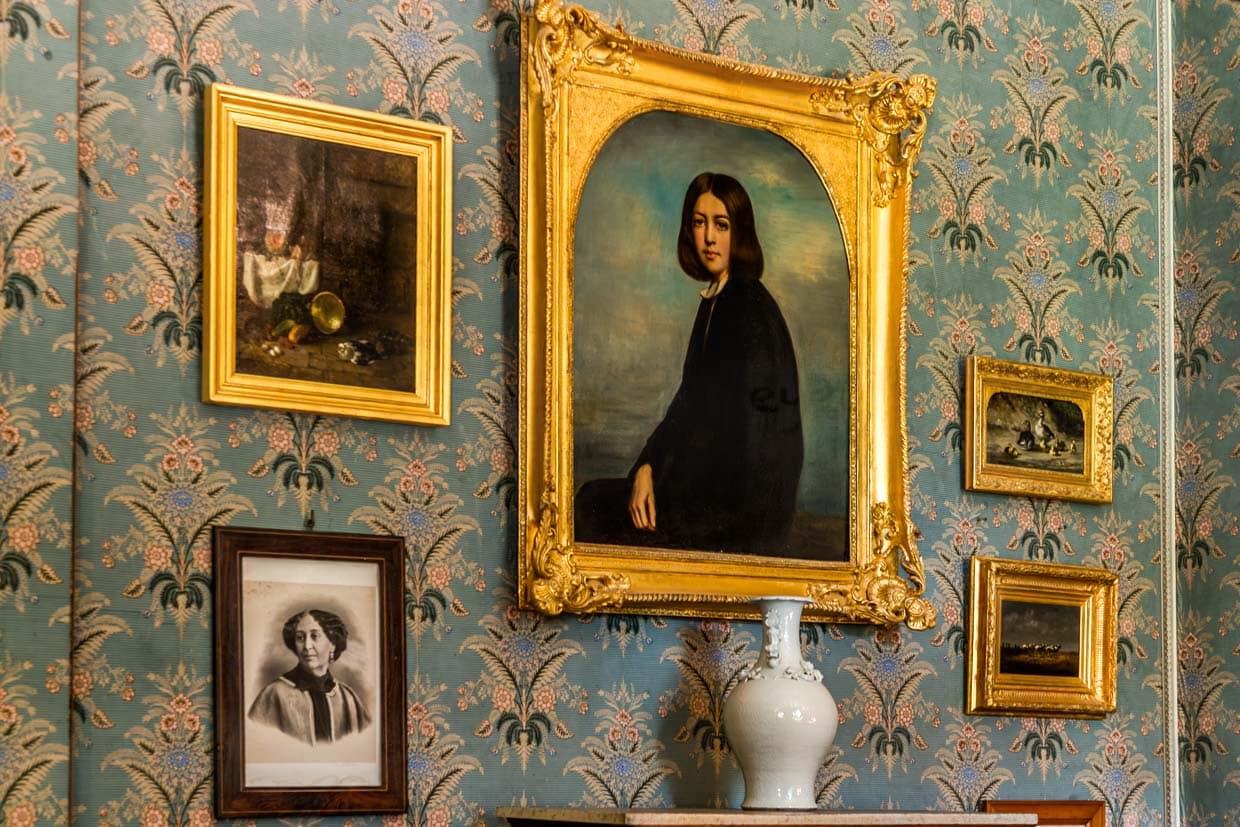 Salon im George-Sand-Haus in Nohant mit Portraits von George Sand und ihrer Familie, hier groß im Bild das Portrait von George Sand als junge Frau / © Foto: Georg Berg