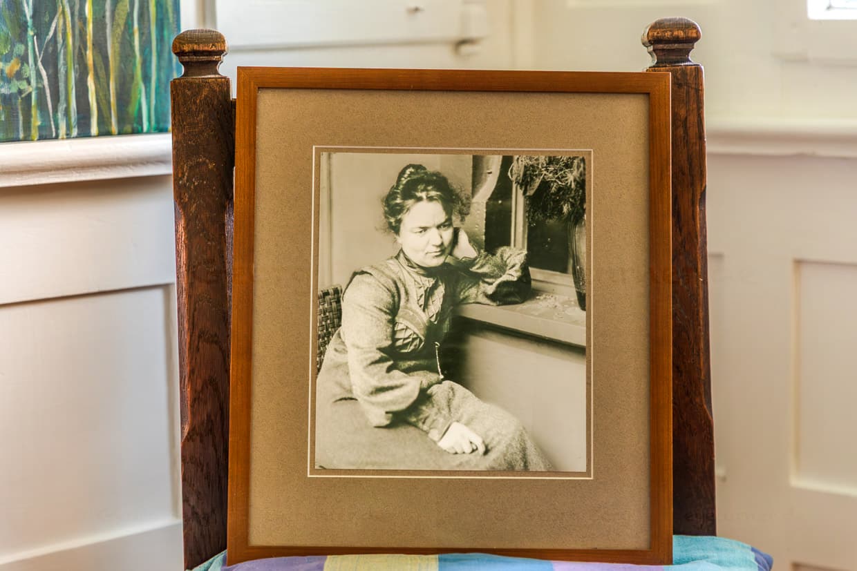 Fotografie im Mia-und Hermann-Hesse-Haus zeigt Mia Hesse sitzend mit ernst-traurigem Gesicht am Fenster ihres Hauses in Gaienhofen / © Foto: Georg Berg