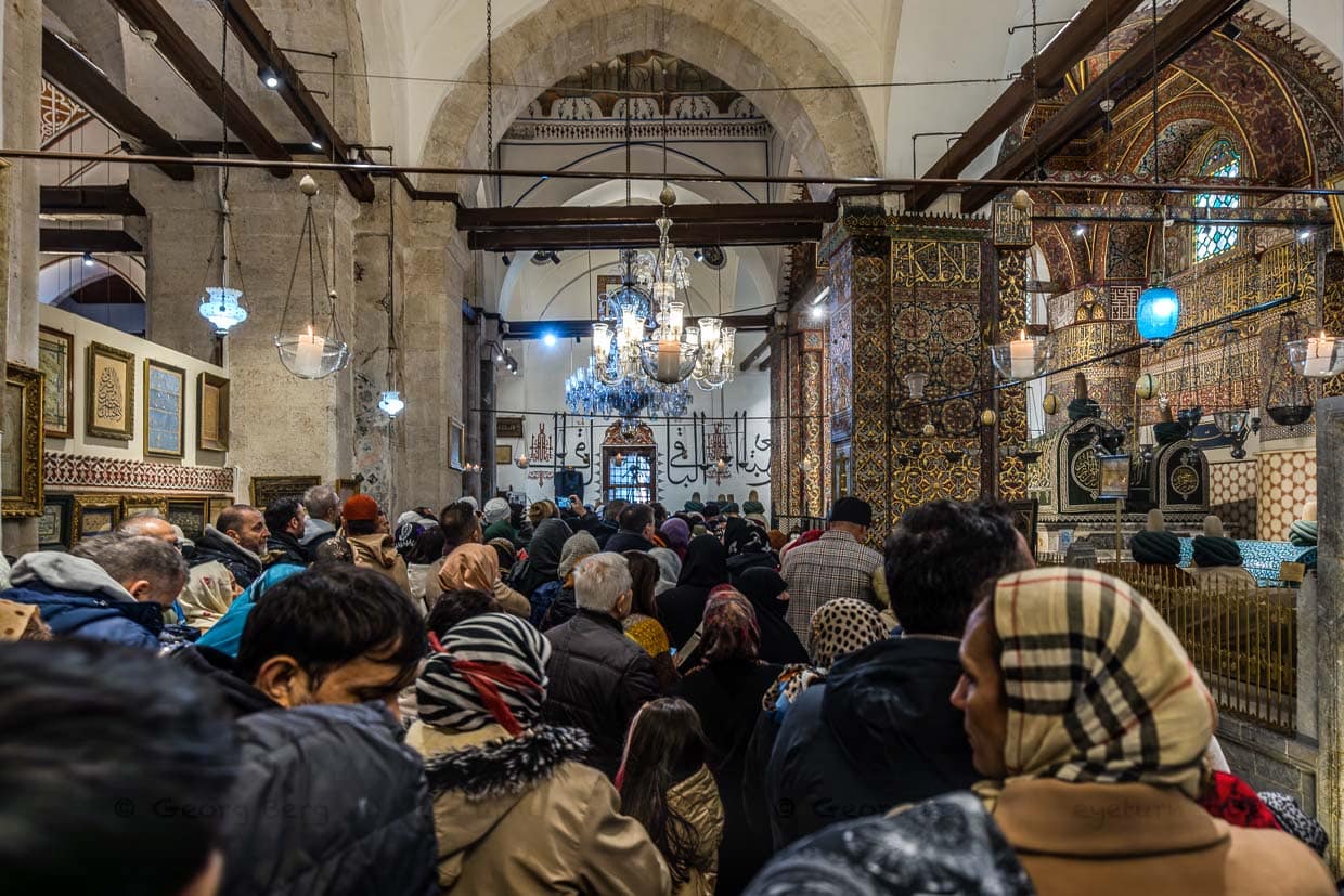 Menschen drängeln sich im Mausoleum von Dschalāl ad-Dīn ar-Rūmī. Direkt neben Rūmīs Kenotaph im zweiten Gewölbejoch des Mausoleums liegt der Sarkophag seines Sohnes Sultan Veled († 1312) / © Foto: Georg Berg