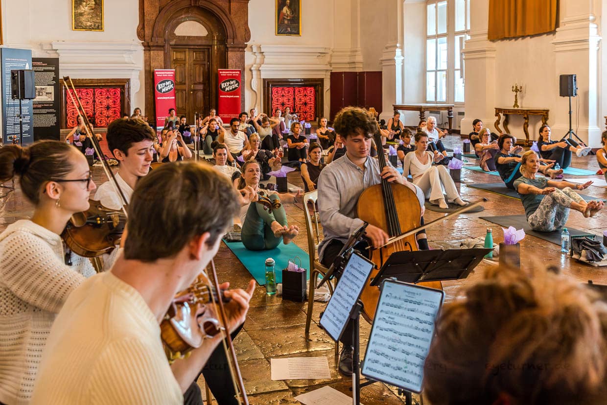 Junge Musiker spielen Streichinstrumente für Yoga-Praktizierende bei einem Event in der Franziskanergasse, Salzburg, Austria