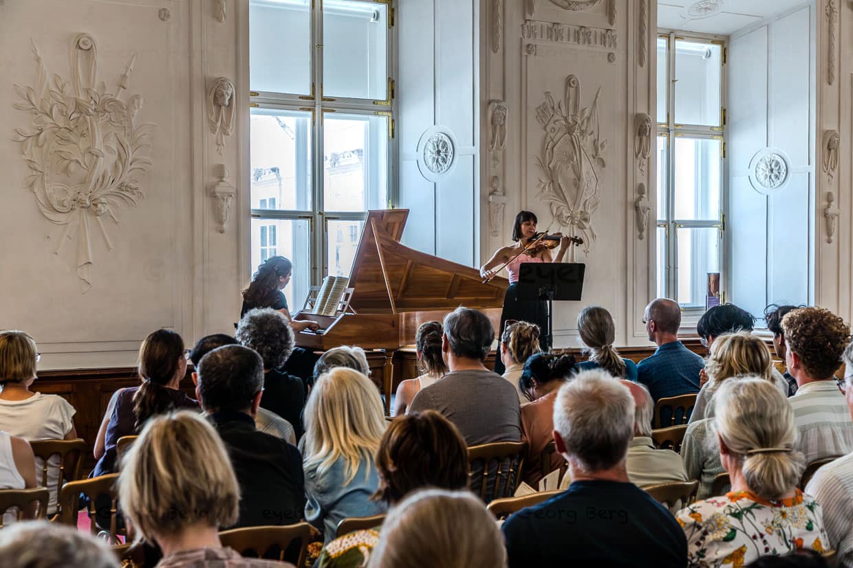 Zwei Musikerinnen spielen klassische Musik vor einem aufmerksamen Publikum in einem prunkvollen Saal am Domplatz Salzburg Austria