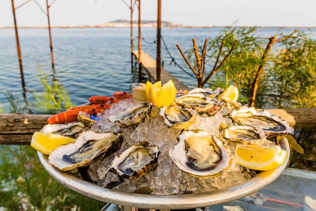 Austernplatte mit Meeresfrüchten im Strandpavillion Le St Pierre Tarbouriech. Hinter der Lagune liegt die Stadt Sète / © Foto: Georg Berg