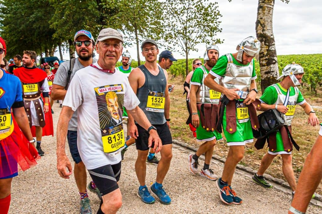 Journalist Georg Berg erfüllt sich einen lang gehegten Traum und nimmt am Marathon des Chateaux du Medoc teil. Während er ein T-Shirt mit Max Headroom, dem investigativem Cyber-Punkfilm von 1985 (dem Jahr des ersten Marathon im Medoc) trägt, wird er bei Kilometer 26 auf Höhe des Chateau Lafite Rothschild von römischen Legionären begleitet / © Foto: Georg Berg