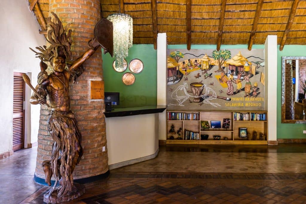 Eingangshalle Makokola Retreat am Lake Malawi bei Mangochi. Die große Figur zeigt den letzten Kämpfer der Ngoni, das Wandbild eine traditionelle Empfangsszene, wenn Gäste ein Dorf erreichen / © Foto: Georg Berg