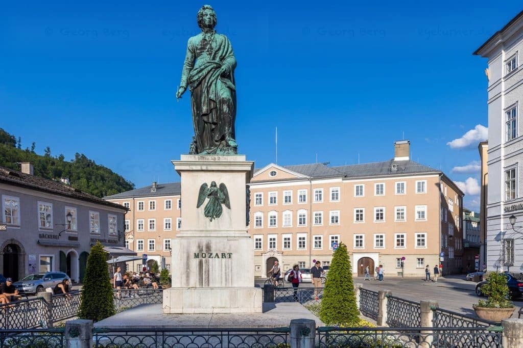 Mozartplatz mit Mozart-Denkmal. Das Werk von Bildhauer Ludwig Schwanthaler wurde 1842 im Beisein beider Söhne Mozarts enthüllt. Mozart hält einen Stift in der Hand und blickt auf die Alte Residenz, dem Ort vieler Vorspiele und Erstaufführungen seiner Werke / © Foto: Georg Berg