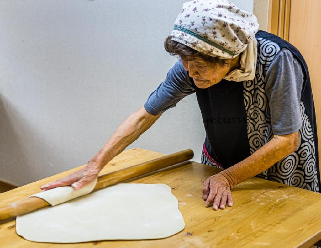 Mit dem langen Nudelholz wird der Sobateig zu einem dünnen Quadrat ausgerollt / © Foto: Georg Berg