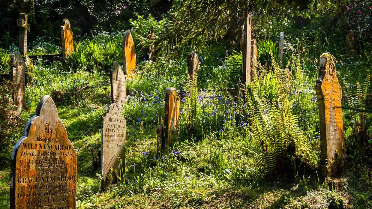 Flechtenbewachsene Gräber in der Abendsonne. Der kleine Friedhof von St. Just / © Foto: Georg Berg