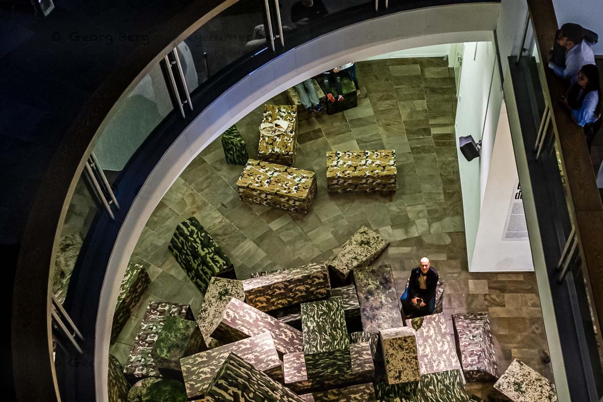 Krieg – immer wieder ein Thema auf der documenta. Sitzmodule in Fleckentarnung werden zweimal in der Woche in einer Performance zu einem Panzer in Originalgröße zusammengebaut / © Foto: Georg Berg