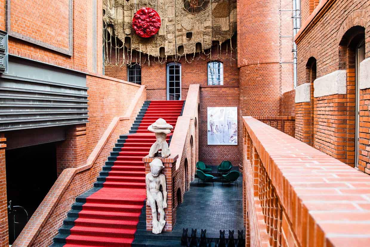 In der Eingangshalle des Hotels finden sich den Raummaßen entsprechend auch die größten Kunstwerke. Darunter der Wandteppich von Piotr Uklański über dem Eingang der Bar und Holzskulpturen von Sylwester Ambroziak am Treppenaufgang / © Foto: Georg Berg