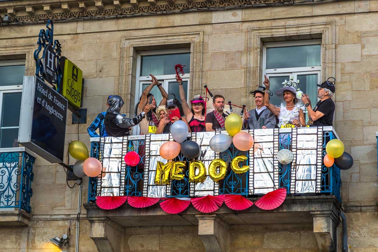 Am Start- und Zielort in Pauillac ist die Stimmung großartig. Auf dem Balkon eines Hotels feiern Läufer und Fans des 36. Marathon des Chateaux du Medoc die Völkerfreundschaft / © Foto: Georg Berg