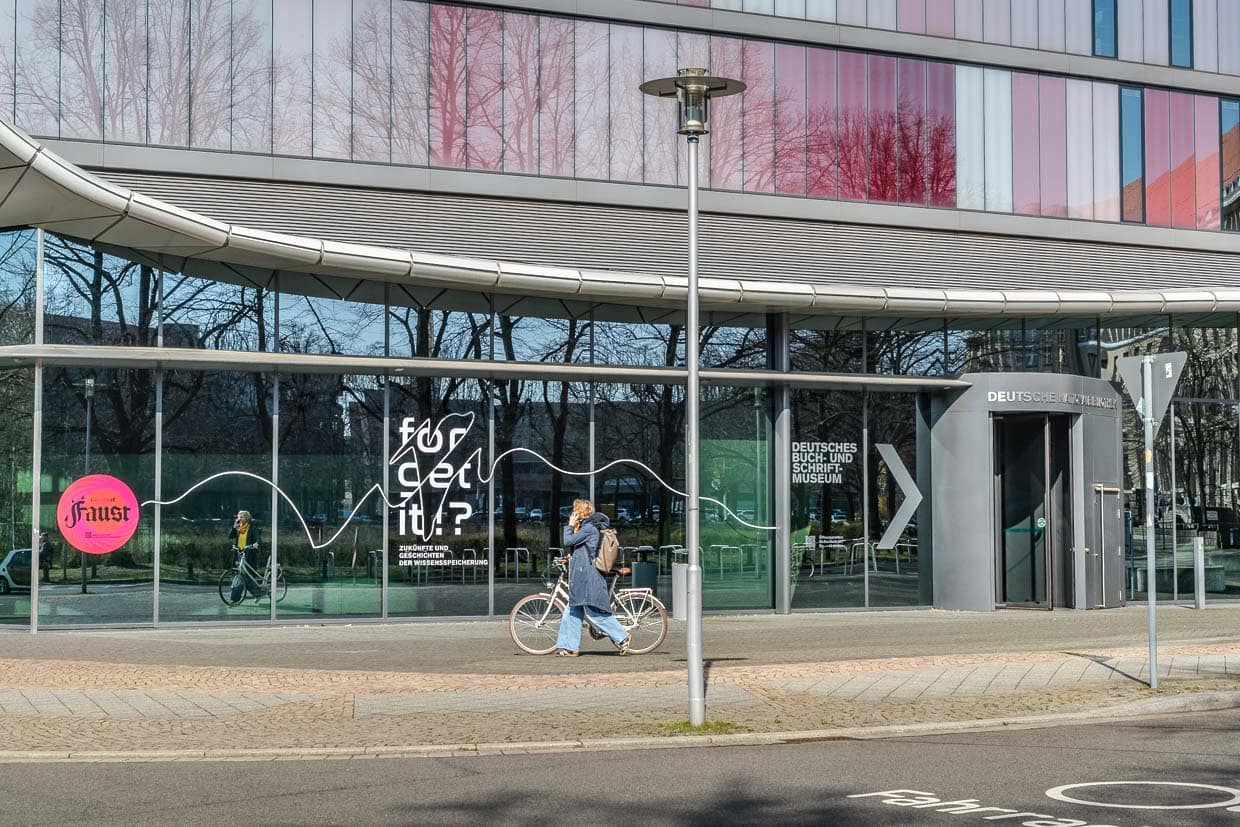 Frau fährt Fahrrad vor dem Deutschen Buch- und Schriftmuseum in Leipzig, Germany