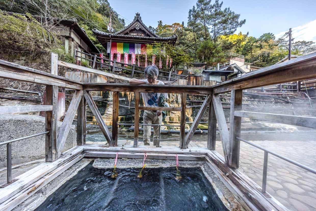 Mann betrachtet heiße Quelle mit traditionellen japanischen Bauten in Tanabe, Japan