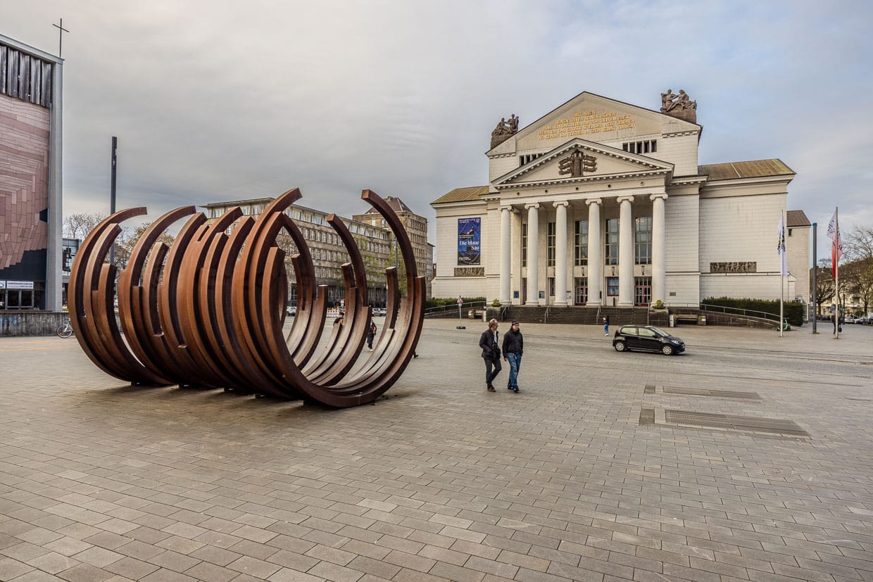 Zwei Männer gehen an einer Skulptur vorbei vor dem Theater Duisburg, Deutschland
