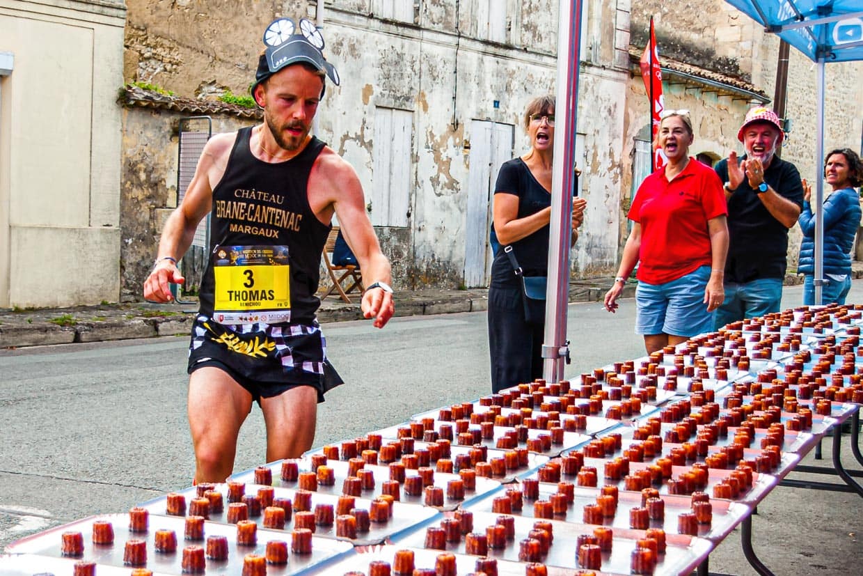 To great applause from the stand attendants, a first runner grabs a bite and helps himself to the 4.000 Caneelés, which the Gironde Department has prepared for the participants / © Photo: Georg Berg