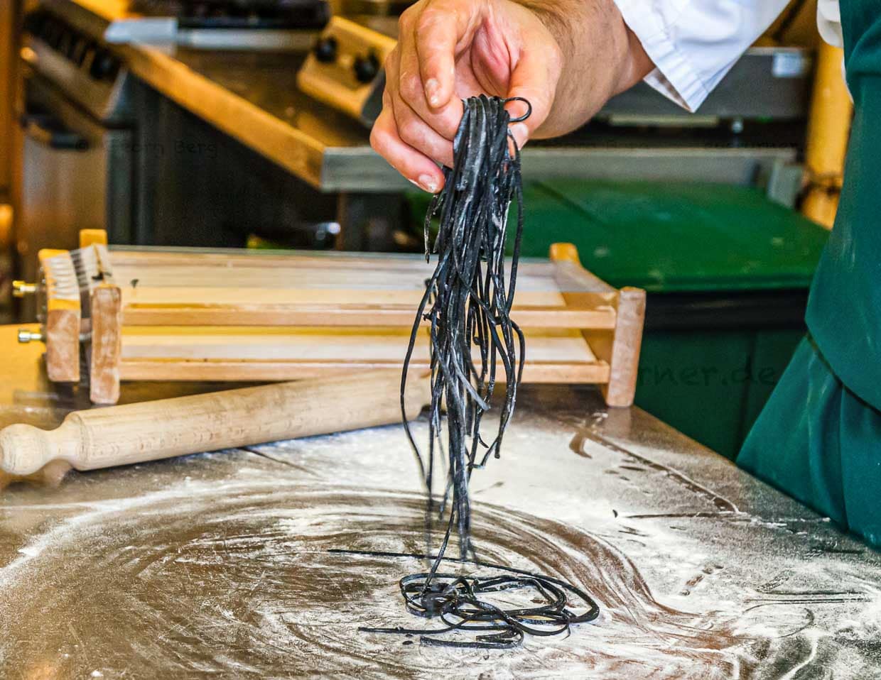 Die einzelnen Schritte der Pastaproduktion mit dem Carraturo. Zuerst wird der Teig mehrmals durch eine Nudelmaschine gedreht, bis er ganz dünn ist. Danach kann der dünne Teiglappen mit einem Nudelholz durch die Drähte gedrückt werden, die ihn in dünne Streifen schneiden. Anschließend kurz bemehlen und erst kurz vor dem Verzehr in Salzwasser al dente kochen. An der Seite des Chefkochs steht Salvatore Piacente, ebenfalls Absolvent der Kochschule Santa Maria, an der schon José Graziosi sein Handwerk lernte / © Foto: Georg Berg
