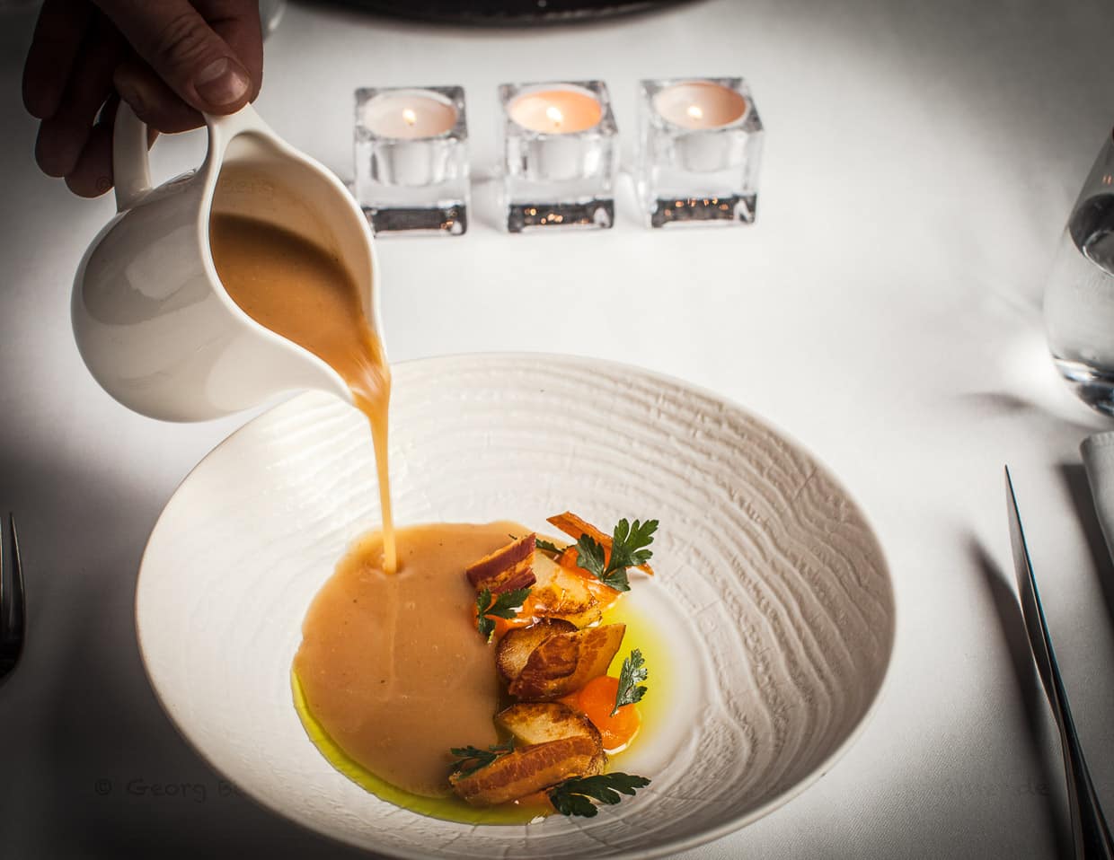 Traditionelle polnische Kartoffelsuppe mit Schinken, Ofenkartoffeln und Kräuteröl und einem bei 62 Grad gestocktem Eigelb / © Foto: Georg Berg