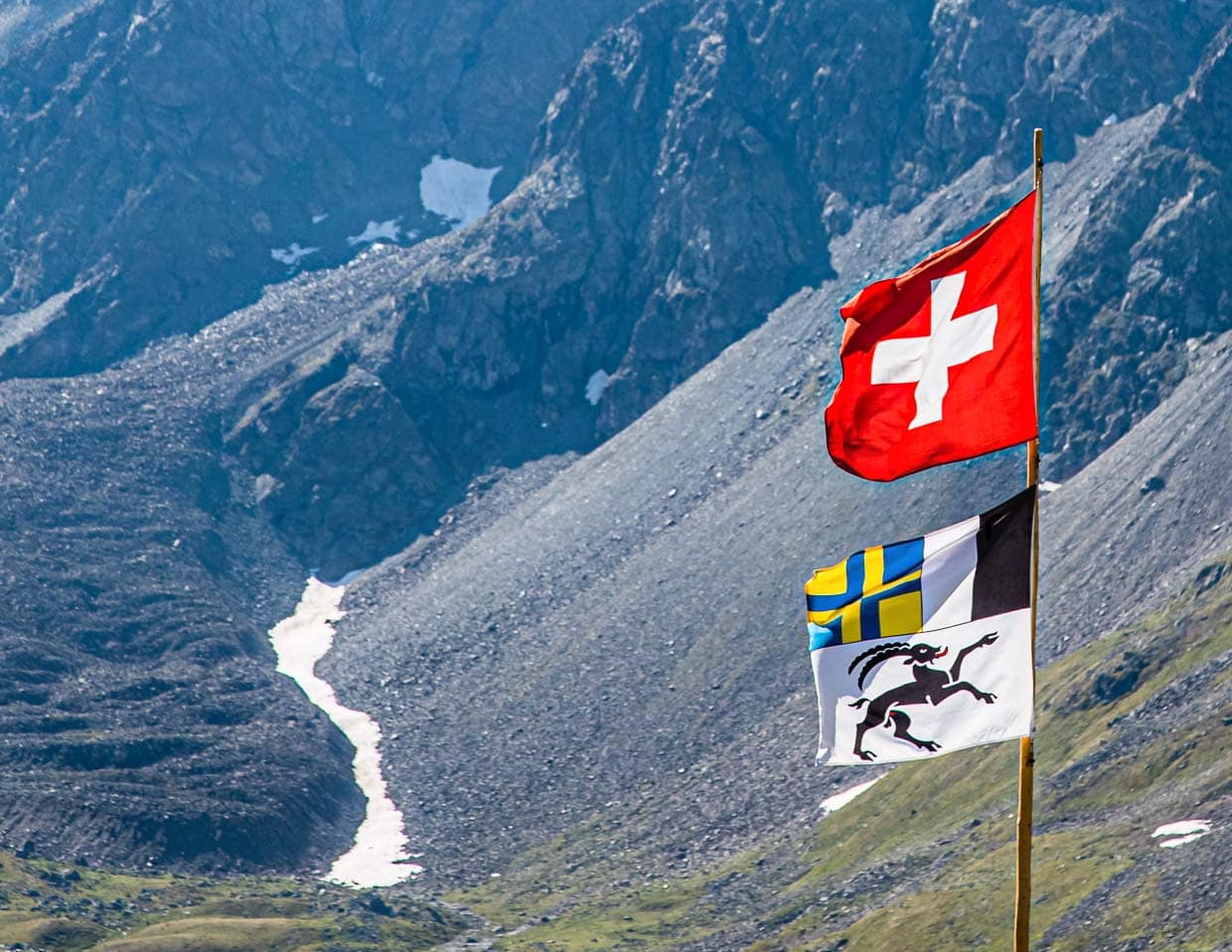 Die Fahne des Kantons Graubünden besteht aus drei Teilen und erinnert damit an die drei Bünde, aus denen der heutige Kanton hervorging. Der schwarze Steinbock als Emblem des Gotteshausbundes, das geteilte Feld für den grauen Bund und das Blau-gelbe Kreuz für den Zehngerichtebund / © Foto: Georg Berg