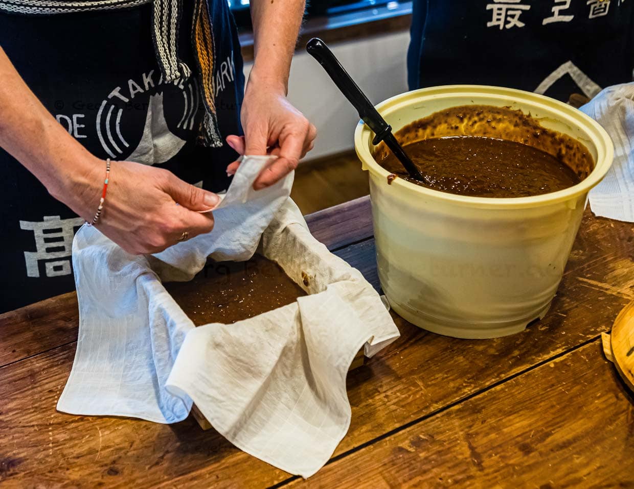 Nach der Führung durch die Manufaktur geht es im wahrsten Sinne des Wortes ans „Eingemachte“. Moromi wird den Workshop-Teilnehmern im kleinen Eimer vorgesetzt. Im Kleinen findet nun statt, was in der Manufaktur mit 1.000 Litern Moromi passiert. Durch die Filterpressung kommen am Ende 800 Liter Sojasauce heraus / © Foto: Georg Berg