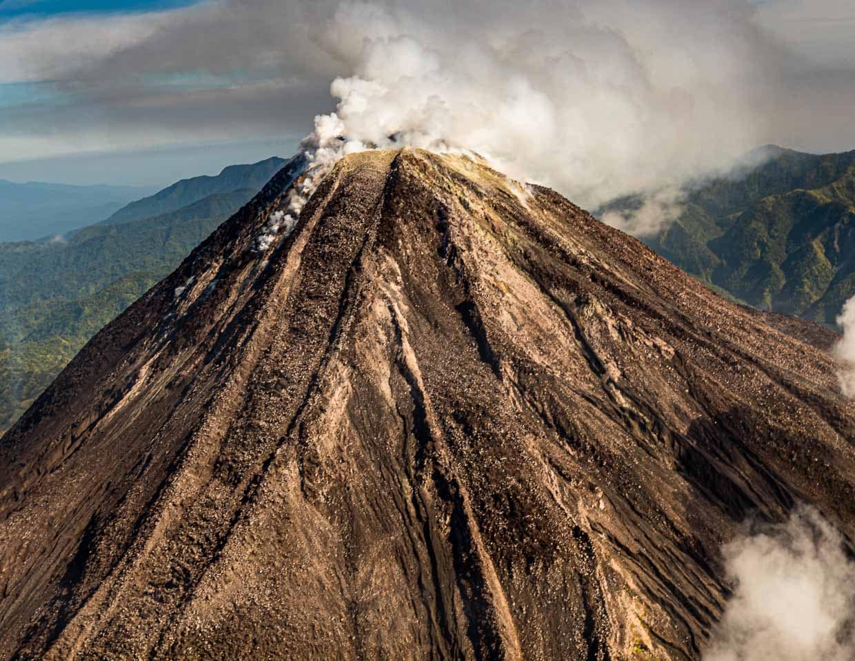 Während wir uns aus der Luft nähern, stößt der Bagana Vulkan Rauchwolken aus / © Foto: Georg Berg