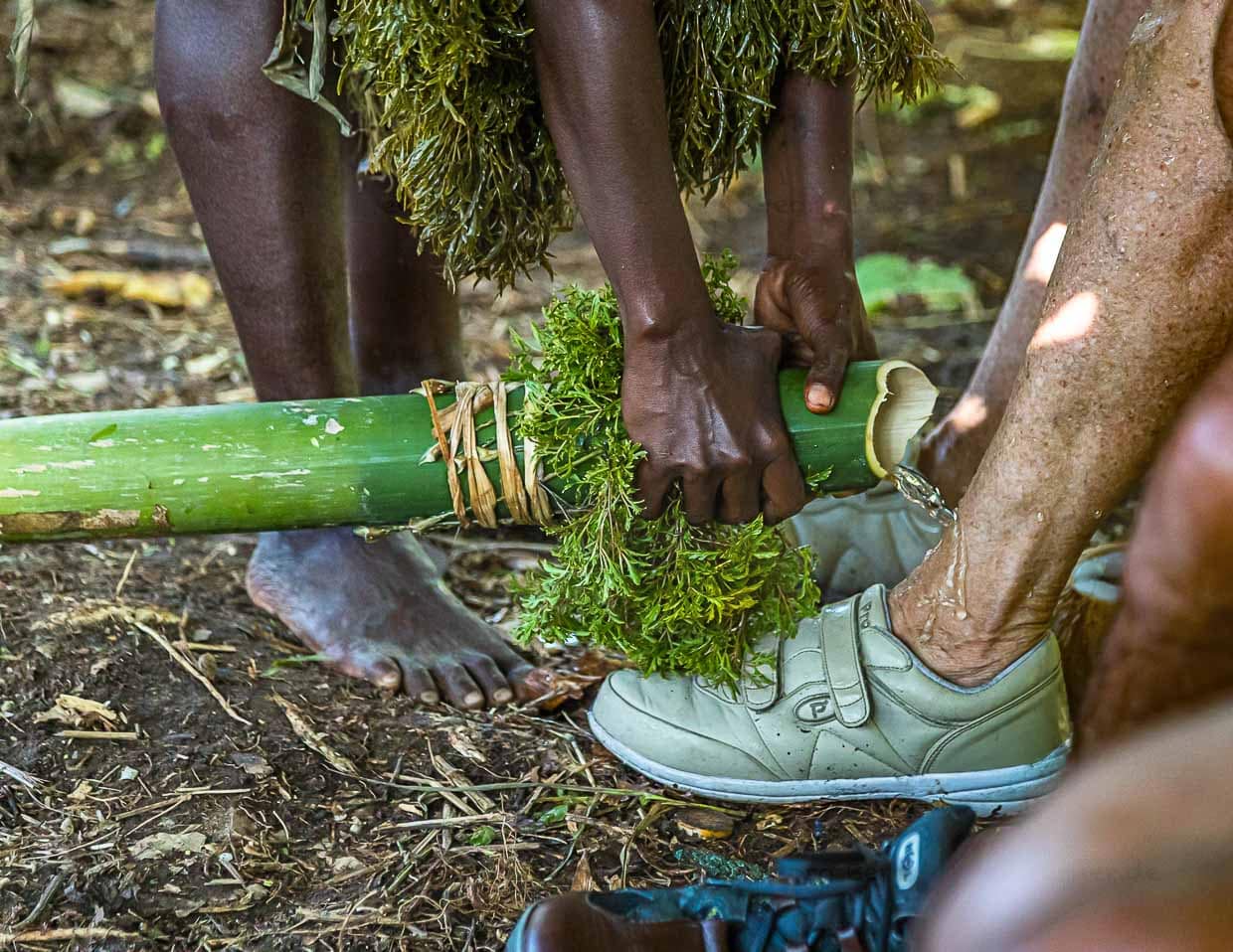 Auf ungewöhnliche Art werden Neuankömmlinge auf Bougainville willkommen geheißen. Mit Wasser aus einem Bambusrohr werden zur Inseltaufe die Füße gewaschen / © Foto: Georg Berg
