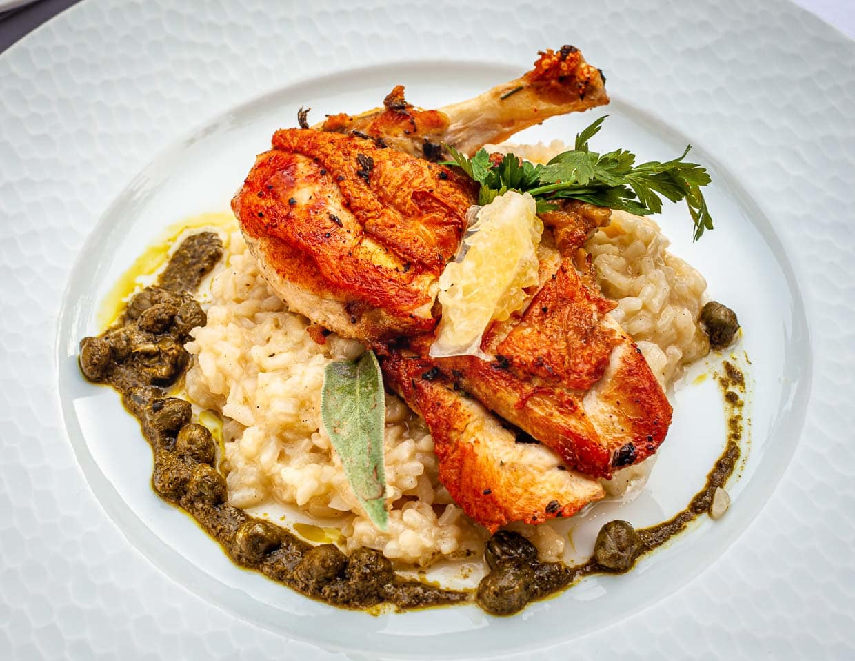 Ein Gericht, auf das man sich freuen kann: Petto di Faraona. Ein umwerfend zitroniges Perlhuhn mit Kapern-Basilikum-Salsa und Zitronen-Risotto / © Foto: Georg Berg