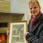 Matthias Trum von der Schlenkerla Bräu vor dem Holzofen mit dem das Grünmalz betrocknet wird. In der Hand hält er eine Zeichnung zur industriellen Malztrocknung nach Sir Nicholas Halse / © Foto: Georg Berg