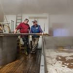 Kurz bevor sich das Brauhaus mit dichtem Nebel füllt steht Zoigl-Braumeister Sepp Neuber mit einem Hausbrauer am Schiff / © Foto: Georg Berg