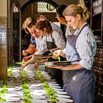 Küchenteam bei der Garnitur vieler Tellergerichten auf dem Flur / © Foto: Georg Berg