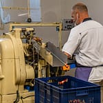 Maschinelle Verpackung von Nuss-Nougat-Pralinen in gold und rot gesteiften Papilloten in der Chocolaterie Frigoulette in Beaufort-sur-Gervanne im Val de Drôme / © Foto: Georg Berg