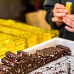 In Handarbeit wird der Bestseller der Schokoladen-Manufaktur Frigoulette in goldenes Papier verpackt. Die Malakoff Praline der Chocolaterie Frigoulette ist in ganz Frankreich erhältlich und besonders beliebt zu Weihnachten. Malakoff gehört zu den geschnittenen Pralinen, die ohne eine zusätzliche Hülle um den Kern auskommen. Die gerösteten Haselnüsse verleihen der Praline eine knusprige Konsistenz / © Foto: Georg Berg