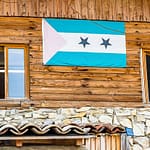 Die Flagge von São Tomé & Príncipe hängt am Gebäude der Schokoladenfabrik Frigoulette. Der Inselstaat im Golf von Guinea trägt auch den Namen Schokoladeninsel. 1822 ließen sich portugiesischen Siedler aus Brasilien auf São Tomé & Principe nieder. Sie brachten auch Kakaopflanzen mit.  Der Boden vulkanischen Ursprungs und die günstigen klimatischen Bedingungen ermöglichten eine rasche Entwicklung des Kakaoanbaus, der 1913 mit 36.000 Tonnen seinen Höhepunkt erreichte. Heute produziert die Insel nur rund 3.000 Tonnen und eine umweltfreundliche und nachhaltige Steigerung der Produktivität ist Firmengründer Bernard Xueref ein wichtiges Anliegen / © Foto: Georg Berg