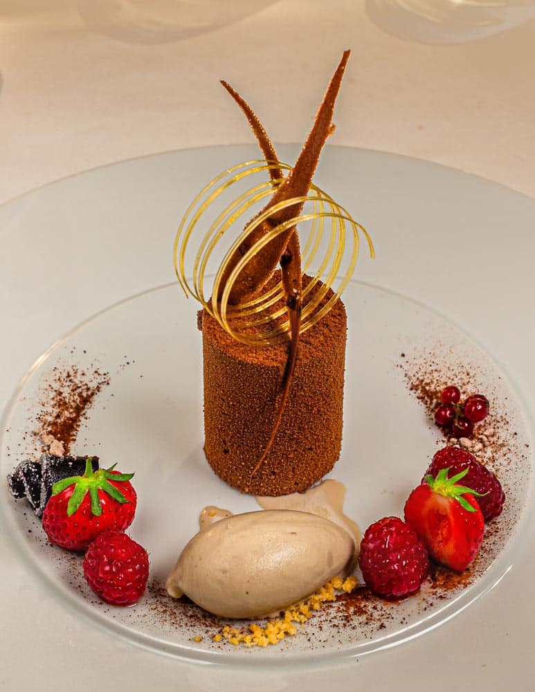 Die wunderschönen Desserts wie dieser Schockokuchen mit Timut Pfeffer an Tonka Eis werden von Florent Jestin dekoriert / © Foto: Georg Berg