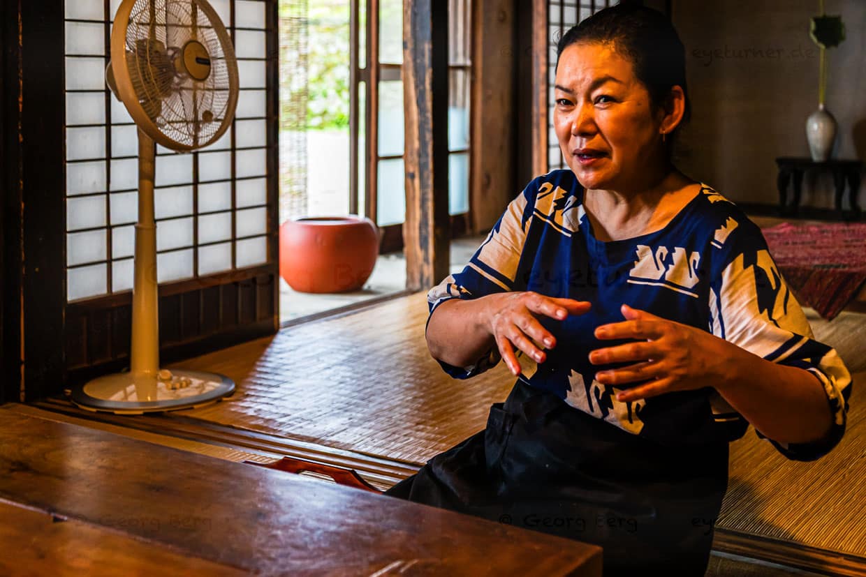 Atsuko Kato in ihrem Speisezimmer erklärt die Prinzipien von Kaiseki. Es wird ein vollwertiges Menü serviert, wobei Zutaten wie Reis und Gemüse direkt von lokalen Produzenten stammen, die Zubereitung erfolgt liebevoll und kreativ, immer inspiriert von den saisonalen Veränderungen und die Präsentation der Speisen vereint visuelle Ästhetik und authentischen Geschmack / © Foto: Georg Berg