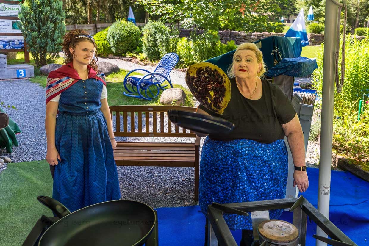 Nicoeltta Kern lässt unter den Augen der Heidelbeerkönigin den Blaubeepfannkuchen fliegen. Der Biergarten im Adventure Golf in Enzklösterle ist im Sommer eine gute Adresse für diese Schwarzwald-Spezialität / © Foto: Georg Berg