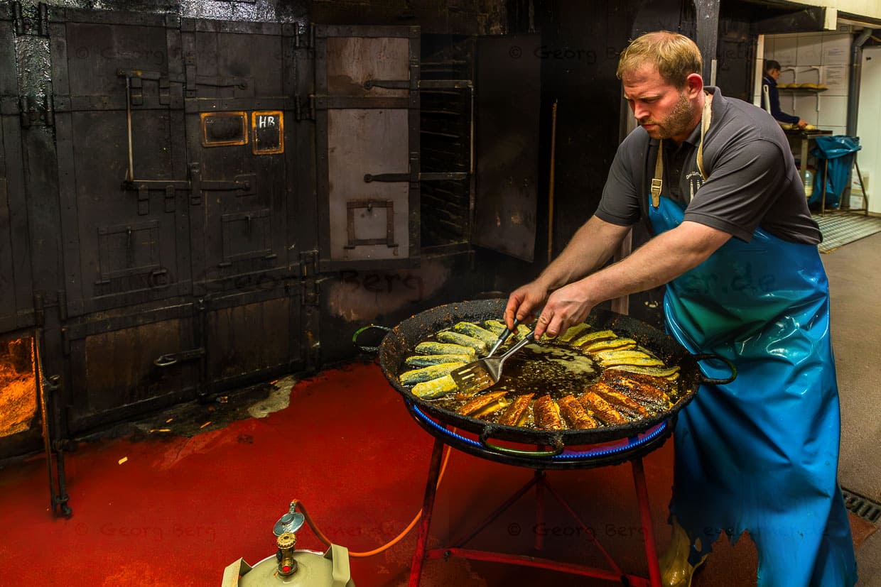 Fish smokehouse Föh, employee turns the fried rings in hot rapeseed oil. In the background, the smoking ovens from the 1920s / © Photo: Georg Berg