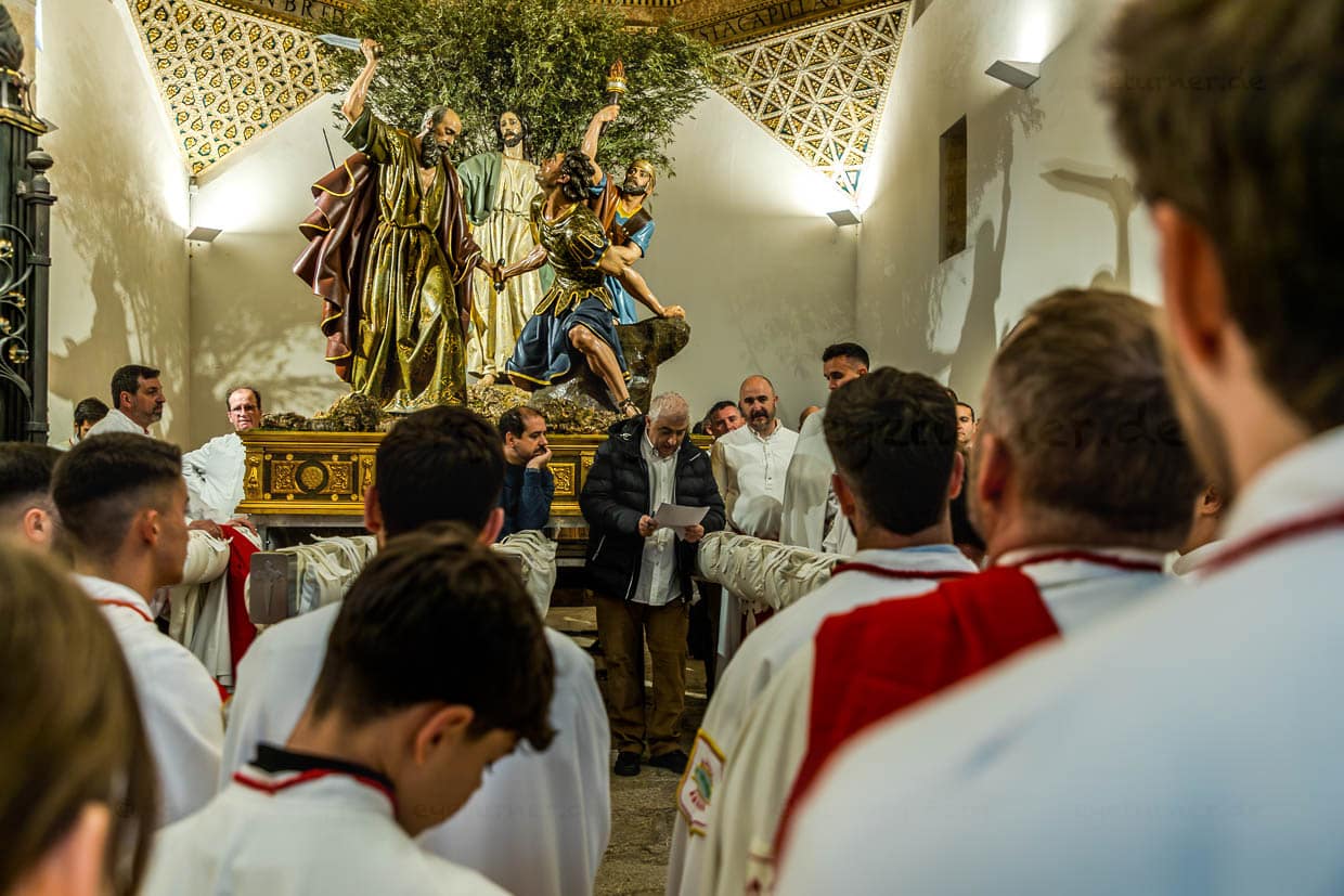 Roll call of the Hermanidad de San Pedro Apóstol in front of the Procesión de Silencio in the Iglesia San Pedro. In the background, the paso depicting Peter cutting off the ear of the servant Malchus after the capture of Christ / © Photo: Georg Berg