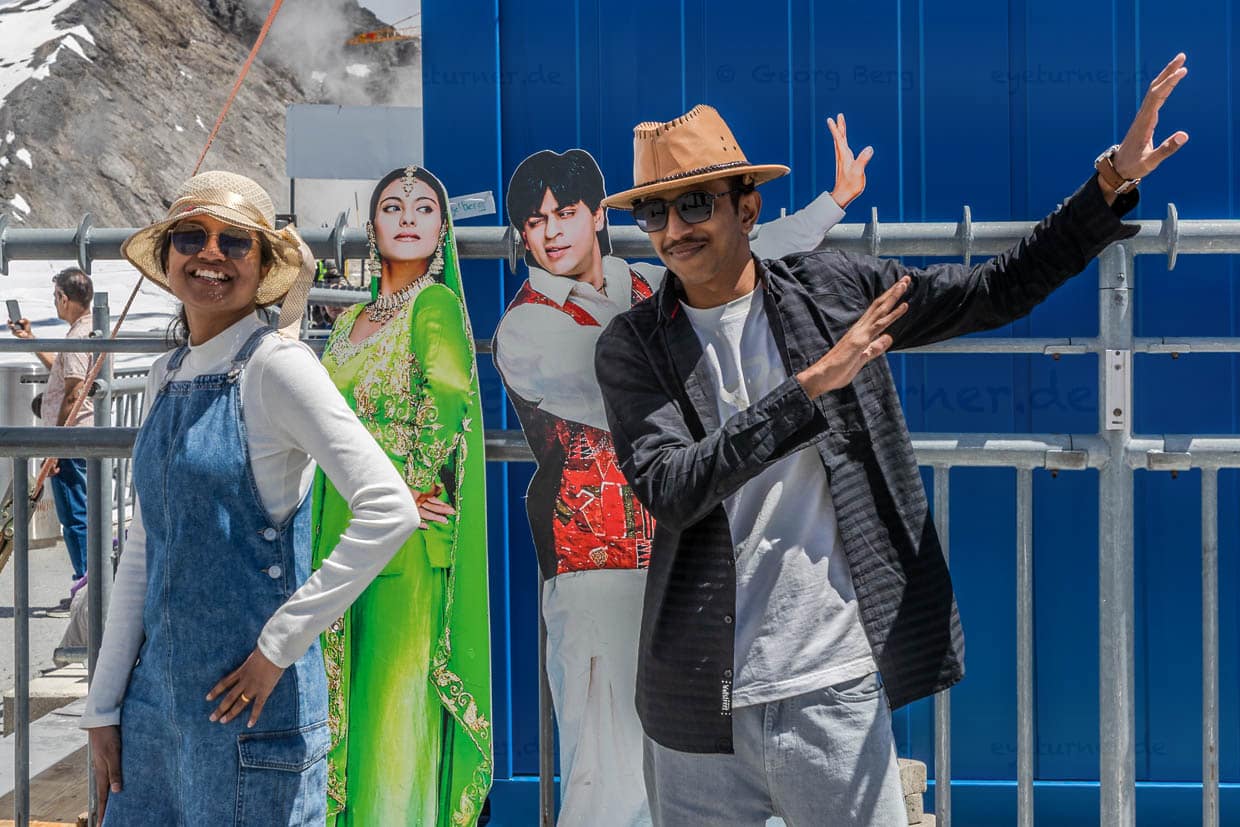 Zwischen Baukränen und Bauarbeitern posen indische Touristen vor einem Pappaufsteller der beiden Bollywood-Schauspieler Shah Rukh Khan und Kajol auf der Bergstation Titlis.  Die beiden Schauspieler gelten als ein berühmtes Leinwandpaar, das in zahlreichen Bollywood-Filmen zusammen spielte und romantische Szenen in der Schweiz gedreht hat / © Foto: Georg Berg