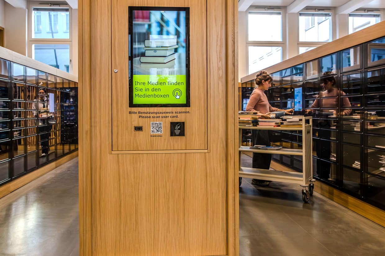 Frau mit Büchern arbeitet an einem Computer in einer Bibliothek, Leipzig, Germany