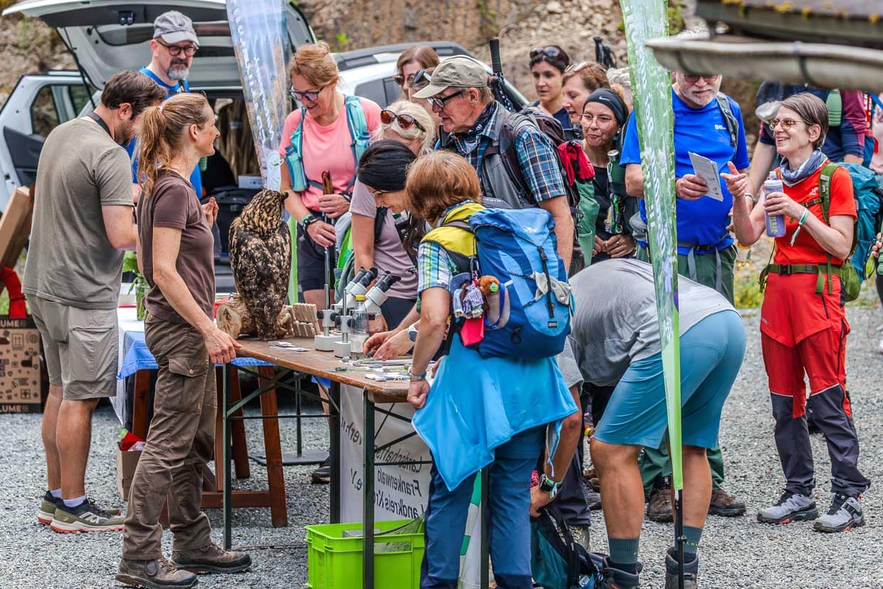 Eine Gruppe von Wanderern und Interessierten betrachtet und lernt über eine Eule Mikroskope und Gesteine an einem Informationsstand an der Kehlbacher Straße in Ludwigsstadt