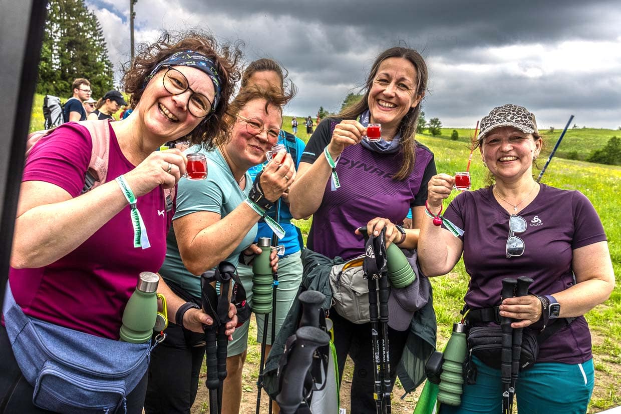 Lachende Wanderinnen feiern mit roten Getränken und Wanderstöcken Am Berg Tettau Germany beim Frankenwald-Event