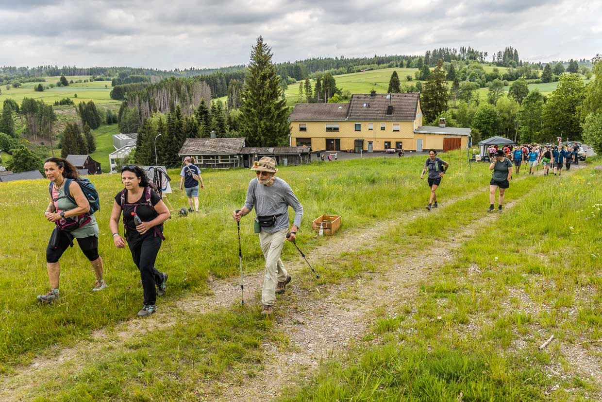 Mehrere Wanderer gehen auf einem Pfad durch grüne Landschaft Am Berg Tettau Germany