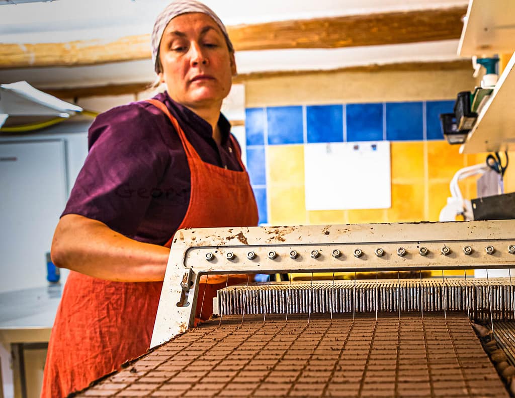 Mitarbeiterin der Chocolaterie Frigoulette in Beaufort-sur-Gervanne beim Zuschnitt von Nougat-Pralinen / © Foto: Georg Berg