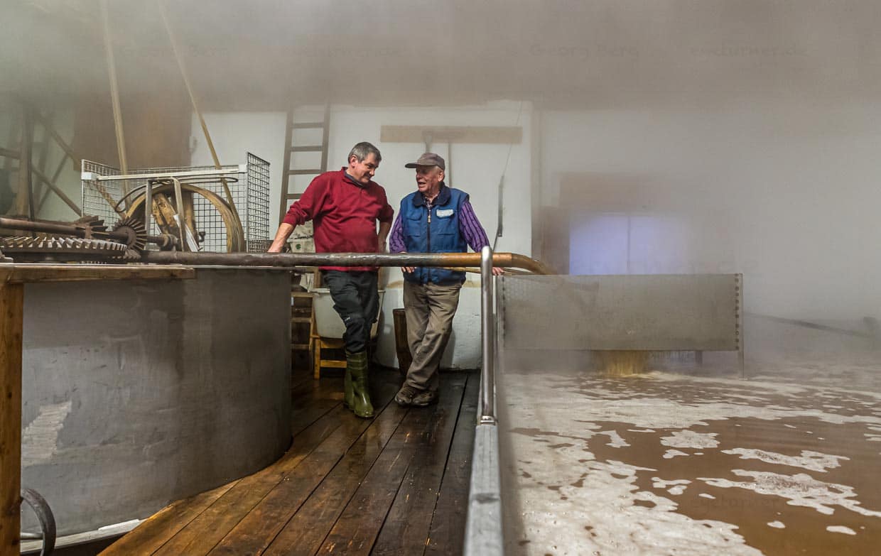 Kurz bevor sich das Brauhaus mit dichtem Nebel füllt steht Zoigl-Braumeister Sepp Neuber mit einem Hausbrauer am Schiff / © Foto: Georg Berg