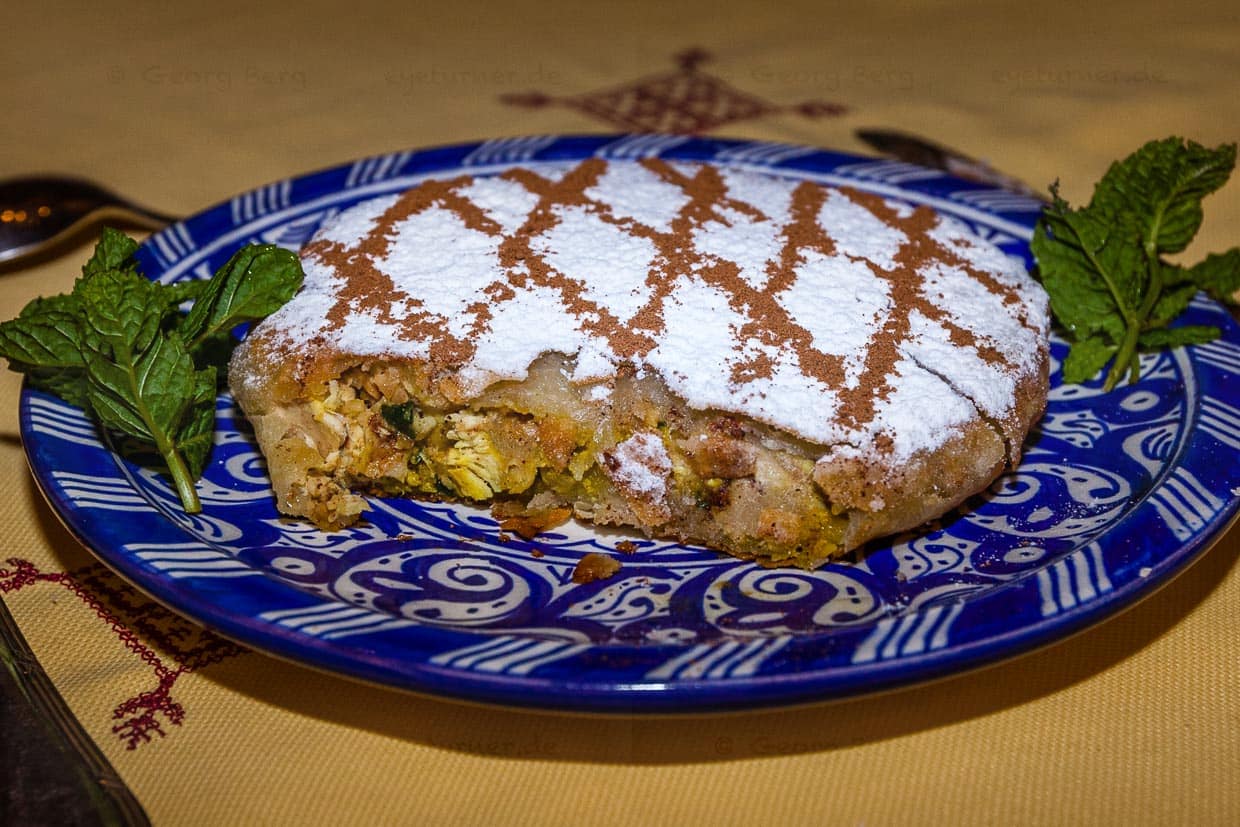 Eine in Marokko Pastilla genannte Blätterteigpastete bildet die Vorspeise. Bei einer angenehm milden Zimtanmutung verträgt sich das Hühnerfleisch erstaunlich gut mit den untergehobenen Eiern, mit Petersilie, Zwiebeln, Mandeln und Ingwer / © Foto: Georg Berg