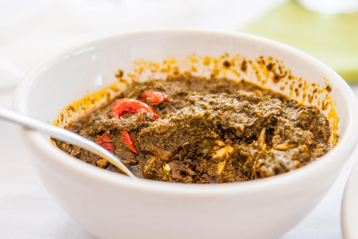 In ihrer Konsistenz gleicht die beliebte scharfe Cassava-Soße püriertem Spinat. Abgebildet ist eine Restaurant-Portion. Hausgemeinschaften essen in Sierra Leone üblicherweise gemeinsam aus einer Schüssel / © Foto: Georg Berg
