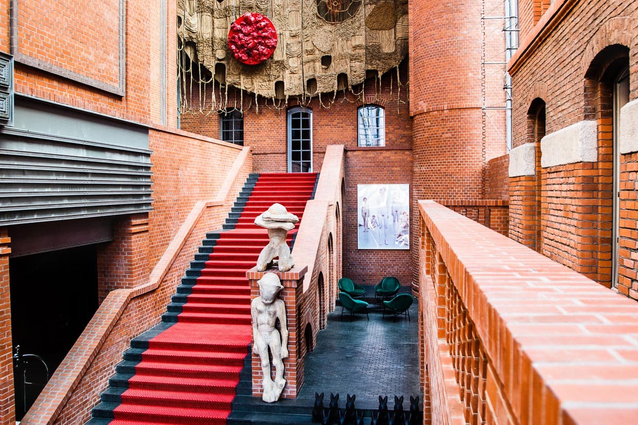 In der Eingangshalle des Hotels finden sich den Raummaßen entsprechend auch die größten Kunstwerke. Darunter der Wandteppich von Piotr Uklański über dem Eingang der Bar und Holzskulpturen von Sylwester Ambroziak am Treppenaufgang / © Foto: Georg Berg