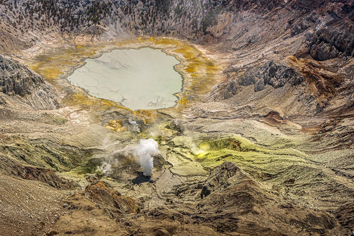 Über dem Gunung Sirung riecht es nach Schwefel und neben einem grauen Kratersee stößt der Vulkan regelmäßig Dampffontänen aus / © Foto: Georg Berg