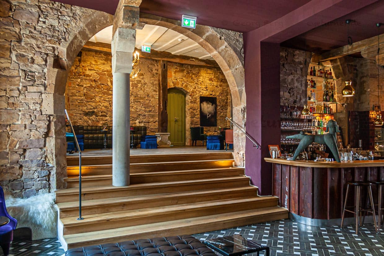 Pudelbar im Hotel Renthof, Kassel, Deutschland. Jeder Bogen ist ein Geschenk, sagt Mitinhaberin Kirstin Kleinkauf. Dieser Bogen, der den Eingangsbereich mit Bistro und Bar verbindet, ist ein besonderer Blickfang, an dem kein Gast achtlos vorbeigeht. Eine kleine Beobachtung am Rande: Beim Betreten der Bar interessieren sich die Männer mehr für die Statik des alten Steins, während die Frauen ihren Blick über die samtigen Sessel und funkelnden Lampen schweifen lassen / © Foto: Georg Berg