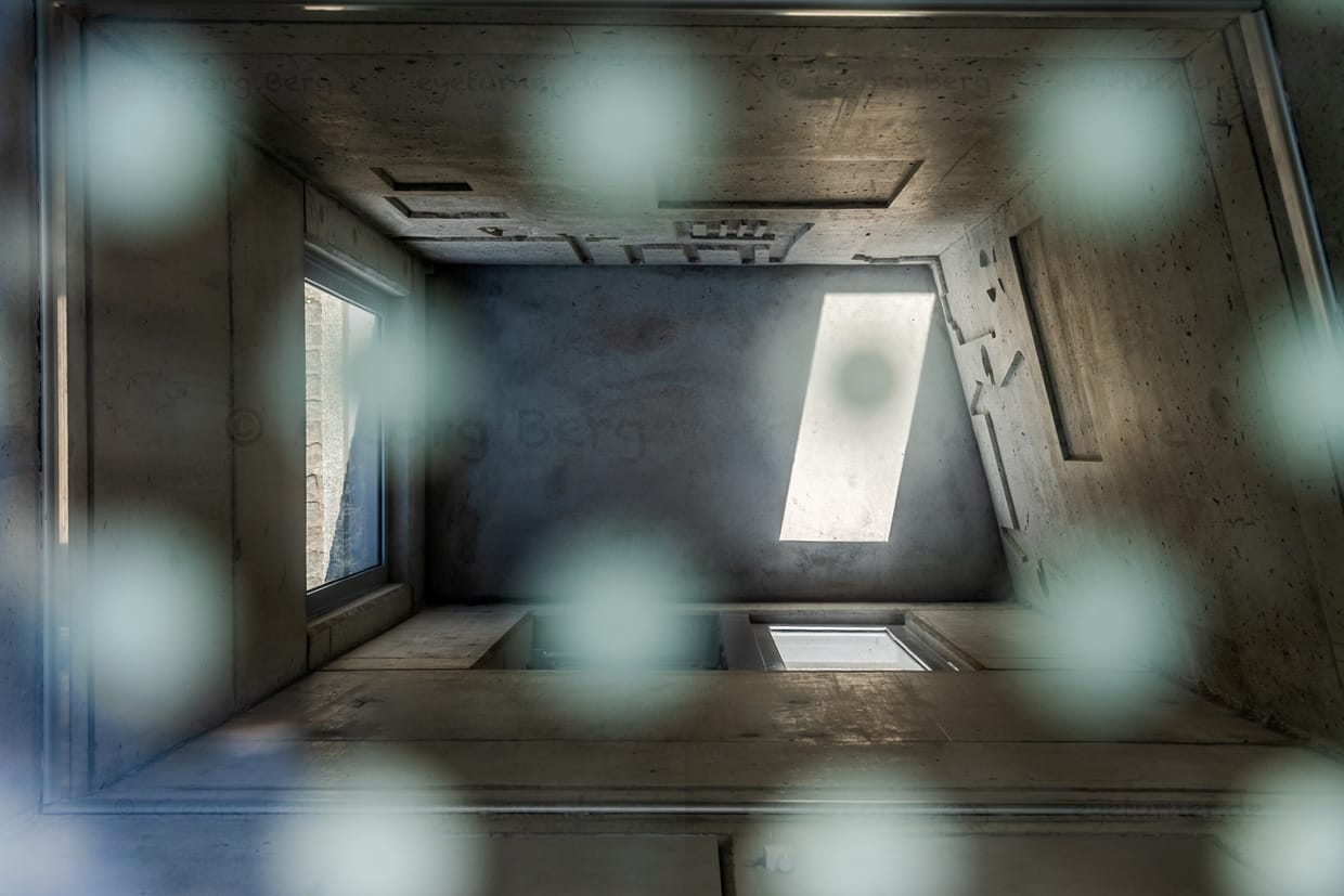 Das Arisierungs-Mahnmal an der Weserpromenade Bremen von oben durch eine vergitterte Öffnung gesehen. Es erinnert seit 2023 an die systematische Enteignung und Ausraubung der Juden während der Zeit des Nationalsozialismus. Entwurf von Evin Oettingshausen. Das Mahnmal steht dort, wo Schiffe damals die geraubten Möbel und Gegenstände aus den besetzten Ländern in Westeuropa nach Bremen brachten. Im Hintergrund Firmensitz von Kühne + Nagel. Die Firma spielte während der NS-Zeit eine zentrale Rolle bei der sogenannten “M-Aktion” / © Foto: Georg Berg